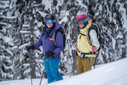 Two skiers standing and smiling at the camera.