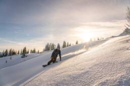 The dawn's embrace: Morning sun casts a golden hue on the untouched powdery slopes of BC, beckoning eager boarders to the best cat skiing experiences at White Grizzly in North America.