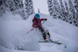 Skier carving through powder-filled pillow fields at White Grizzly cat skiing in BC, Canada.