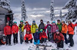 Group of elated guests convening for a picture, capturing their excitement after an incredible day of deep snow lines at White Grizzly cat skiing in BC, Canada.