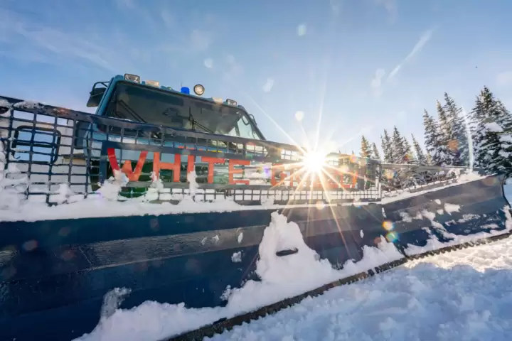 The Best Cat Skiing company in BC. Where adventure begins: the gleaming front blade of a White Grizzly snow cat, with sunlight filtering through its metal, ready for action in BC, Canada.